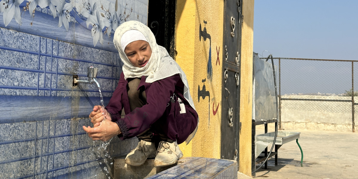 Syrian girl is washing hands at non formal education center in Syrian camp.