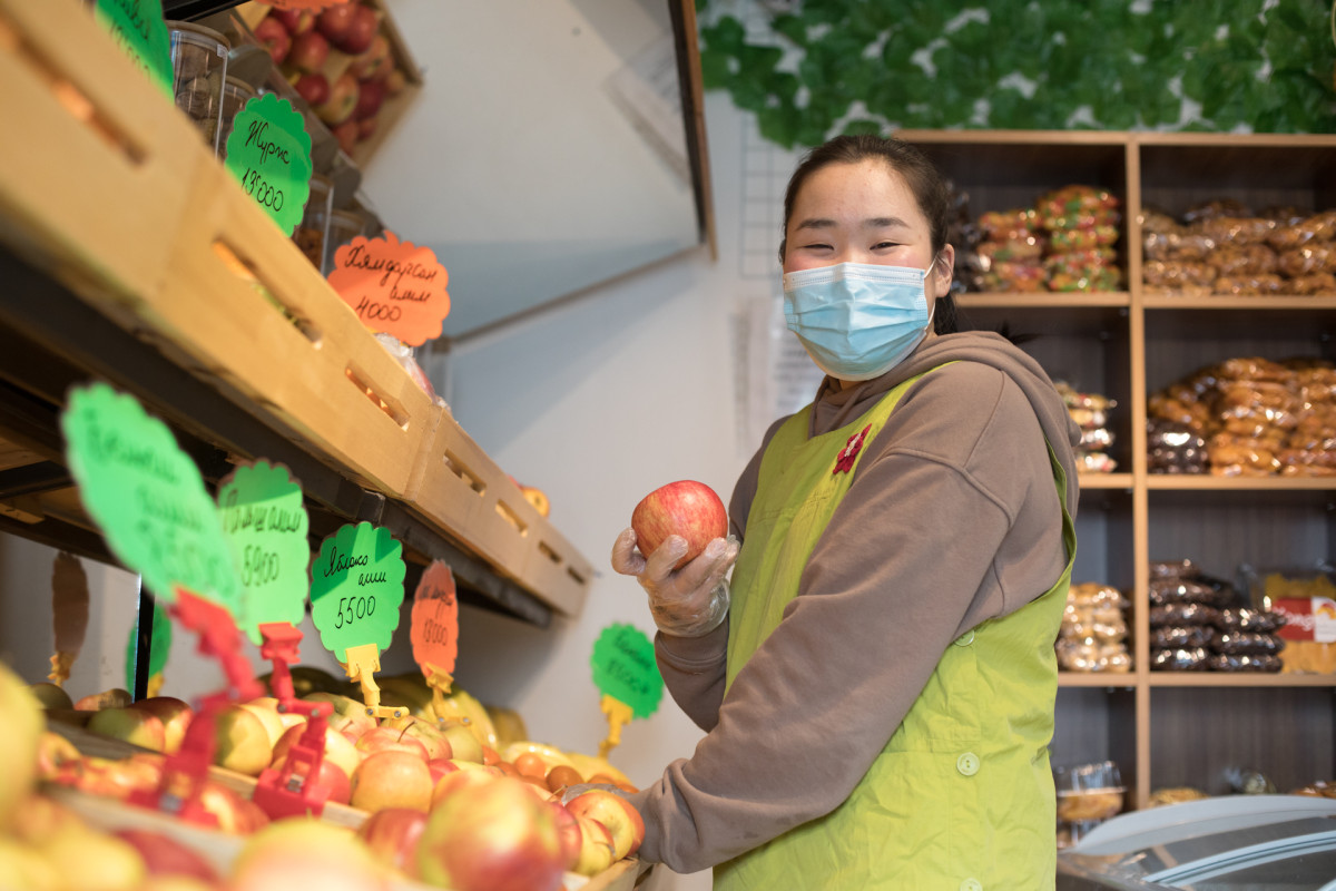 Masked store girl holds apple